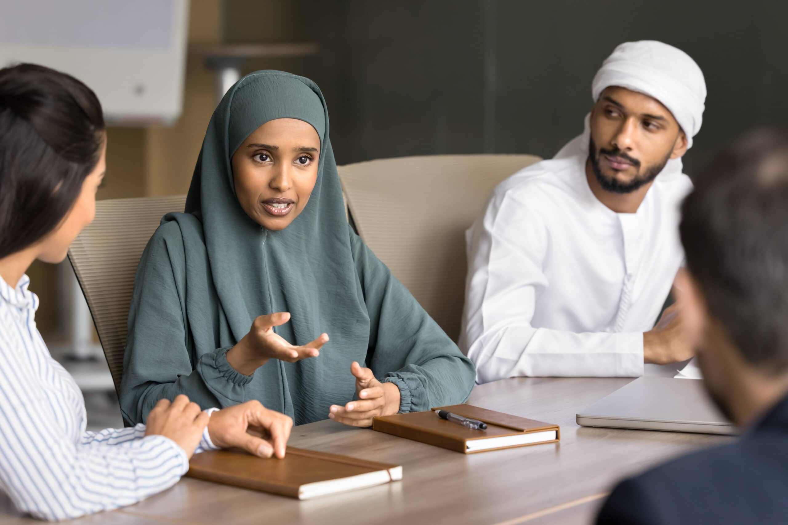 Young Arabic Businesswoman Speak To Multiracial Team At Meeting Table